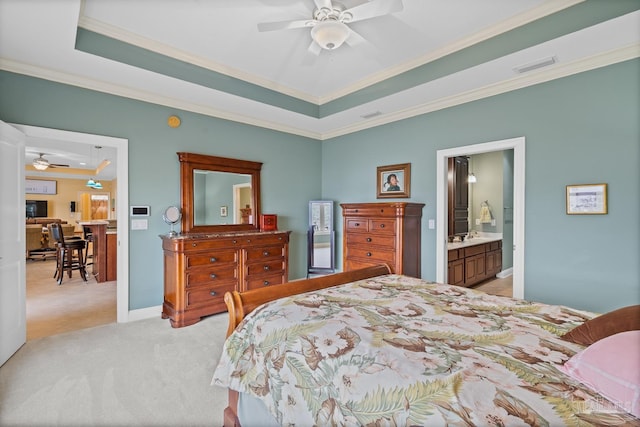 carpeted bedroom with a raised ceiling, ensuite bath, ceiling fan, and ornamental molding