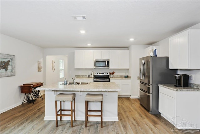 5451 Peach Dr, Pace, FL 32571 - kitchen featuring stainless steel appliances, a center island with sink, a breakfast bar area, light wood finished floors, and recessed lighting