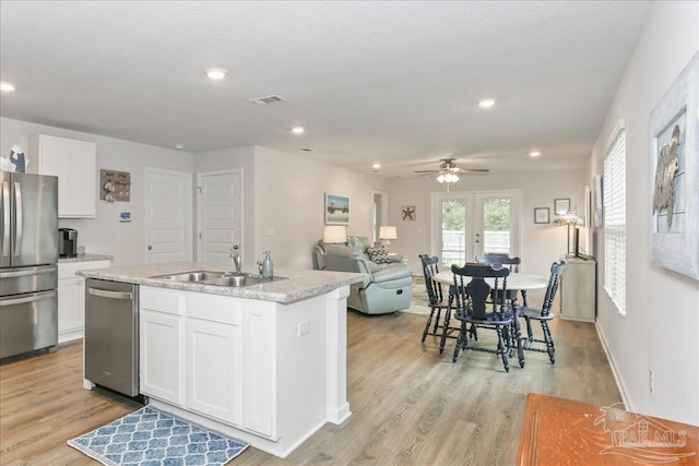 5451 Peach Dr, Pace, FL 32571 - kitchen featuring appliances with stainless steel finishes, white cabinetry, light wood-style flooring, a center island with sink, and open floor plan