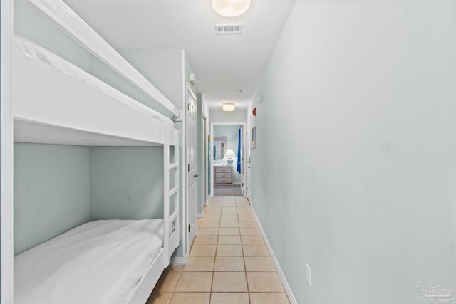 hall featuring light tile patterned floors and a textured ceiling