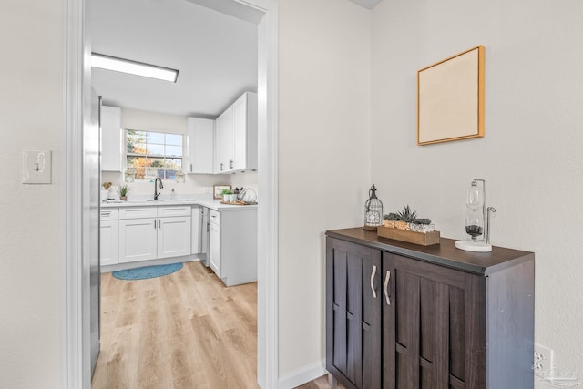 bar featuring white cabinets, light wood-type flooring, and sink