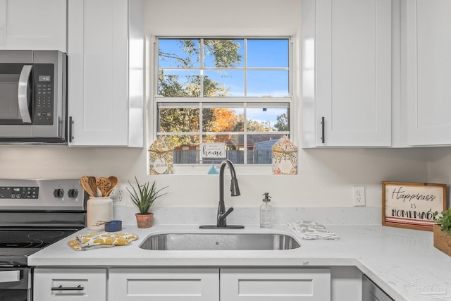 kitchen featuring light stone countertops, sink, white cabinets, and stainless steel appliances