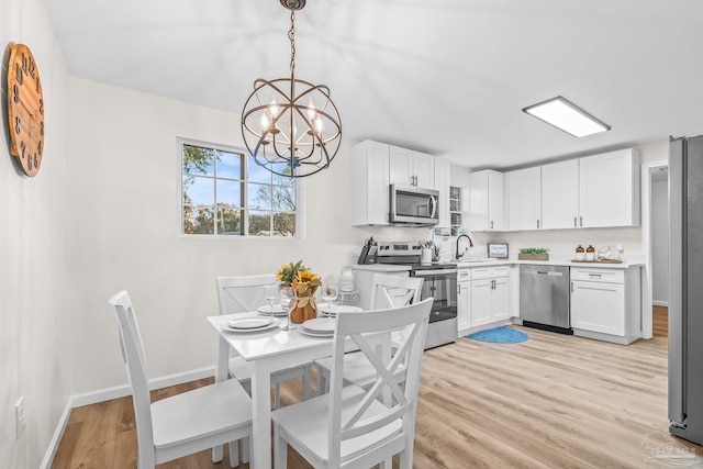 dining space featuring light hardwood / wood-style floors, sink, and a chandelier