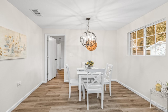 dining area with hardwood / wood-style flooring and an inviting chandelier