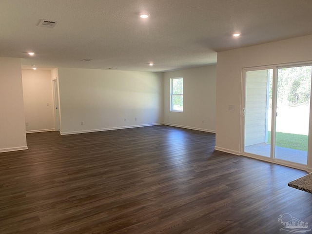 unfurnished room with dark wood-type flooring, a wealth of natural light, and a textured ceiling