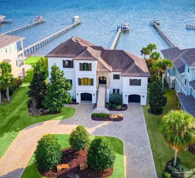 view of front of property featuring a tiled roof, a water view, an attached garage, and stucco siding