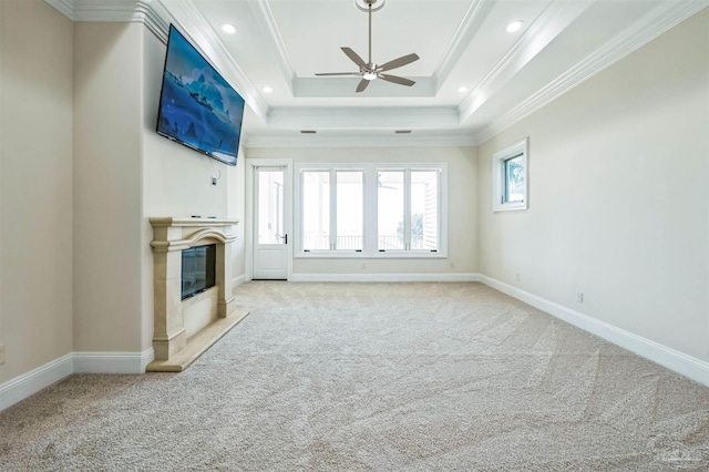 3995 W Madura Rd, Gulf Breeze, FL 32563 - unfurnished living room with light colored carpet, a ceiling fan, a high end fireplace, a tray ceiling, and ornamental molding