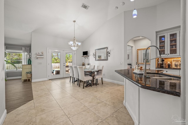 dining room with light tile patterned floors, visible vents, high vaulted ceiling, and a notable chandelier