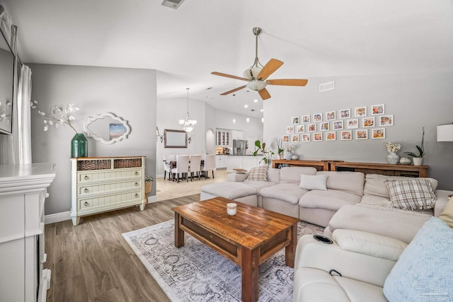 living room featuring baseboards, visible vents, wood finished floors, and ceiling fan with notable chandelier