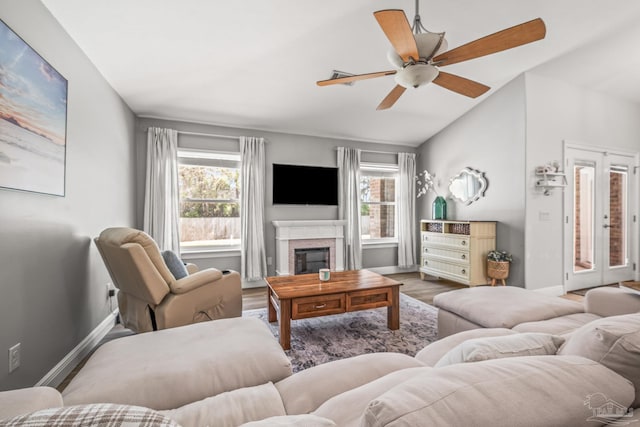 living room featuring ceiling fan, plenty of natural light, a glass covered fireplace, and baseboards