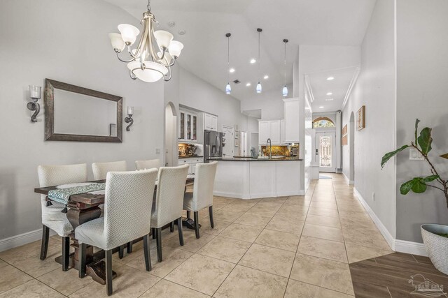 dining area featuring high vaulted ceiling, baseboards, arched walkways, and a notable chandelier