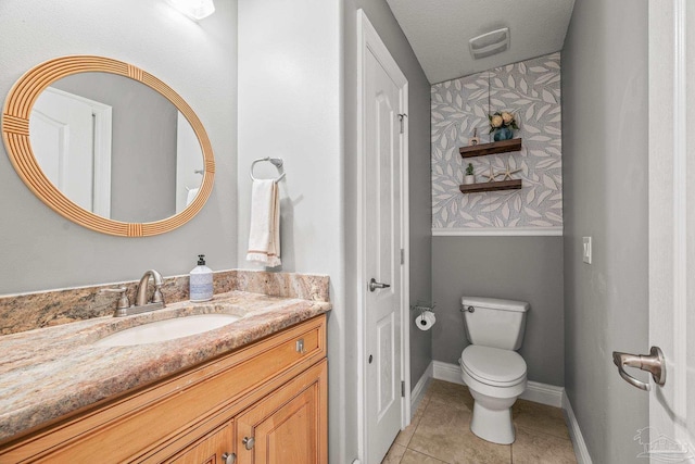 bathroom featuring visible vents, toilet, vanity, baseboards, and tile patterned floors