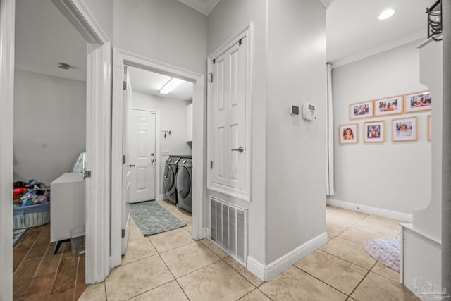 hallway featuring baseboards, visible vents, washing machine and clothes dryer, and light tile patterned floors