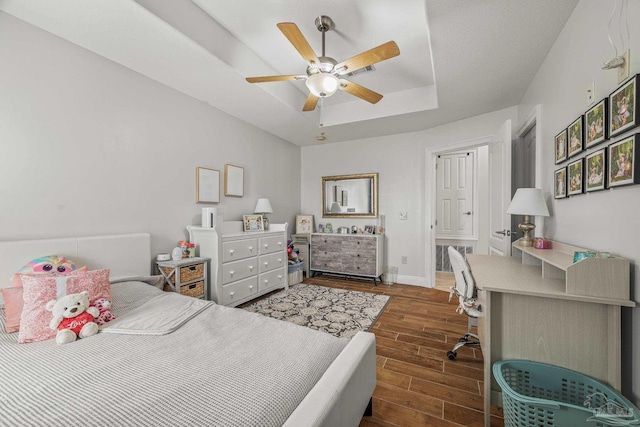 bedroom with wood tiled floor, baseboards, a raised ceiling, and a ceiling fan