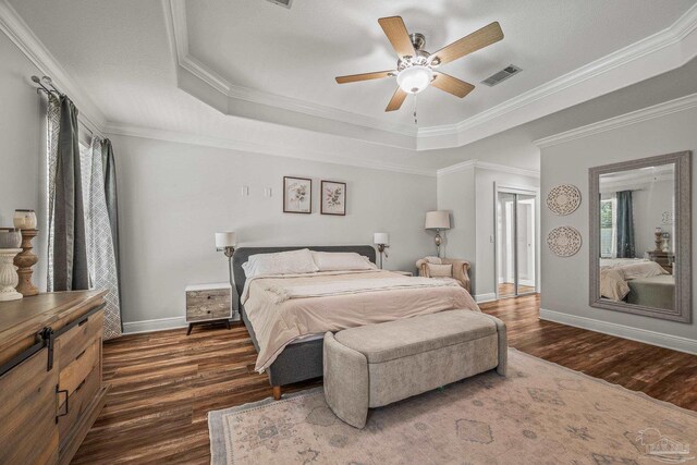 bedroom featuring visible vents, dark wood finished floors, and a tray ceiling