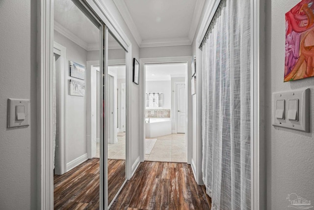 hall featuring dark wood-style floors, ornamental molding, and baseboards