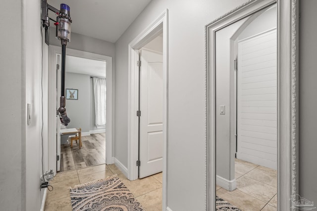 hallway with light tile patterned floors and baseboards