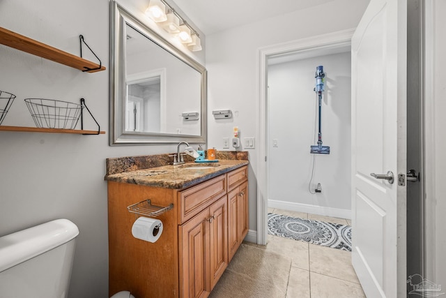 bathroom featuring tile patterned flooring, baseboards, vanity, and toilet