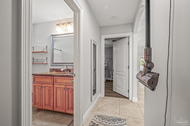 hallway with a sink, baseboards, and light tile patterned floors