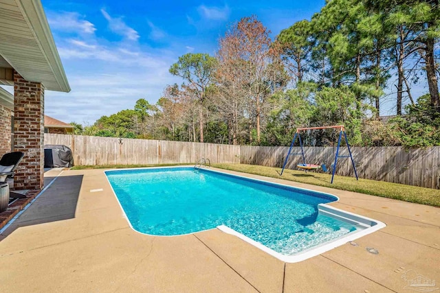 view of swimming pool featuring a patio area, a fenced backyard, a fenced in pool, and a playground