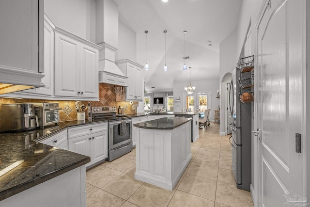 kitchen with arched walkways, white cabinets, appliances with stainless steel finishes, a peninsula, and light tile patterned flooring