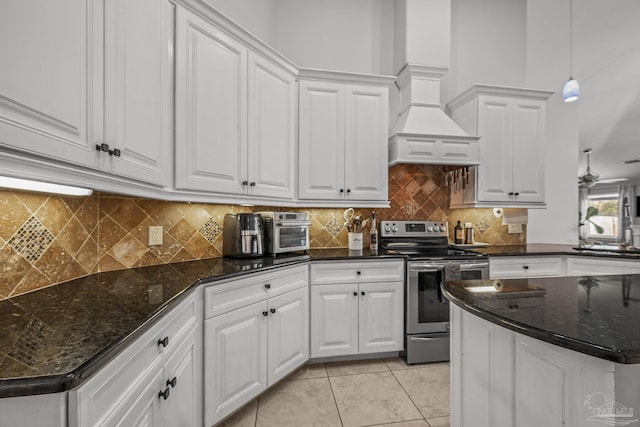 kitchen with light tile patterned floors, electric range, decorative backsplash, dark stone counters, and white cabinetry