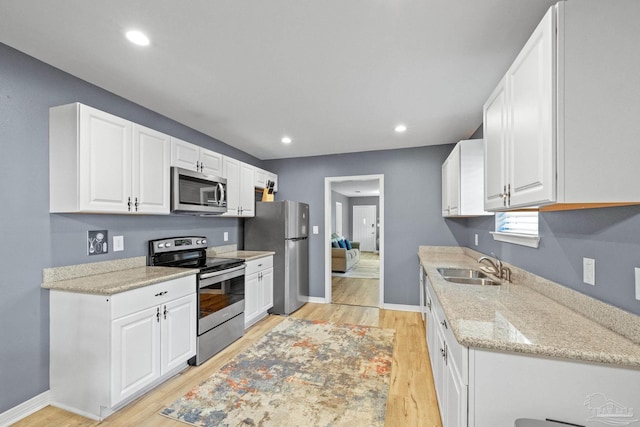 kitchen with white cabinetry, appliances with stainless steel finishes, and light hardwood / wood-style flooring