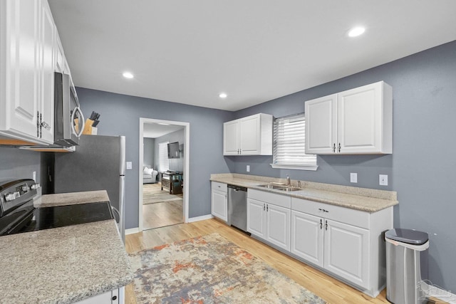 kitchen with sink, white cabinets, light wood-type flooring, and appliances with stainless steel finishes