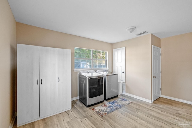 laundry area with separate washer and dryer and light hardwood / wood-style flooring