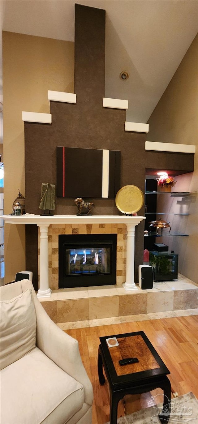 living room with vaulted ceiling, wood finished floors, and a tile fireplace