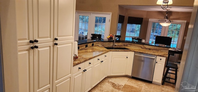 kitchen featuring hanging light fixtures, a sink, dishwasher, and dark stone counters