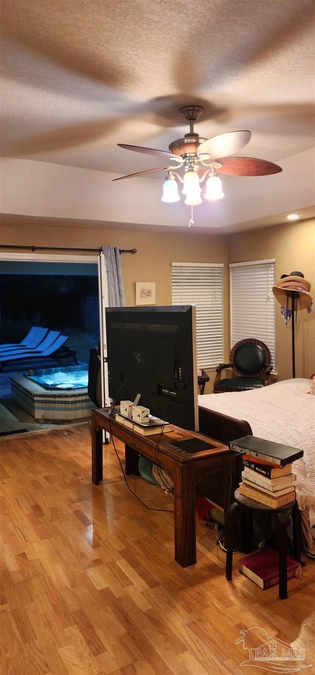 living room featuring a ceiling fan, a textured ceiling, and light wood-type flooring