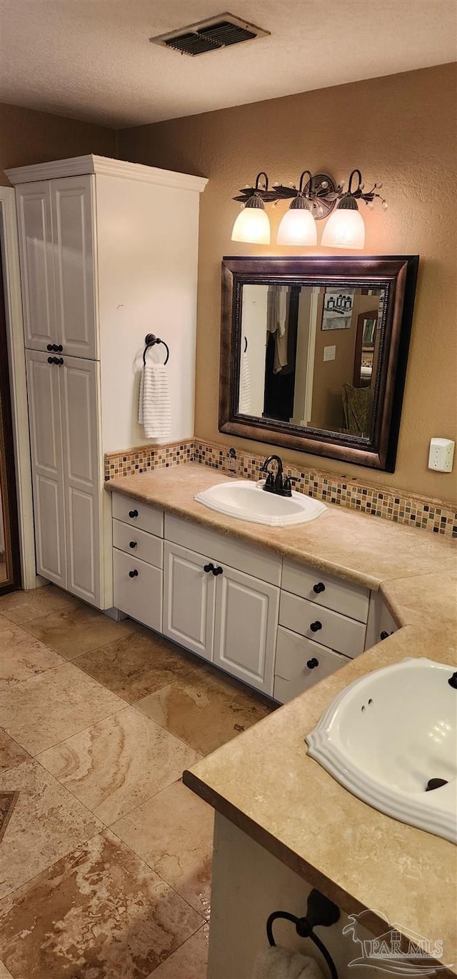 bathroom featuring backsplash, vanity, and visible vents