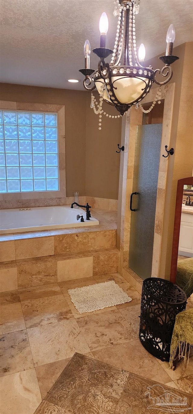 full bath featuring an inviting chandelier, a sink, a textured ceiling, and a bath