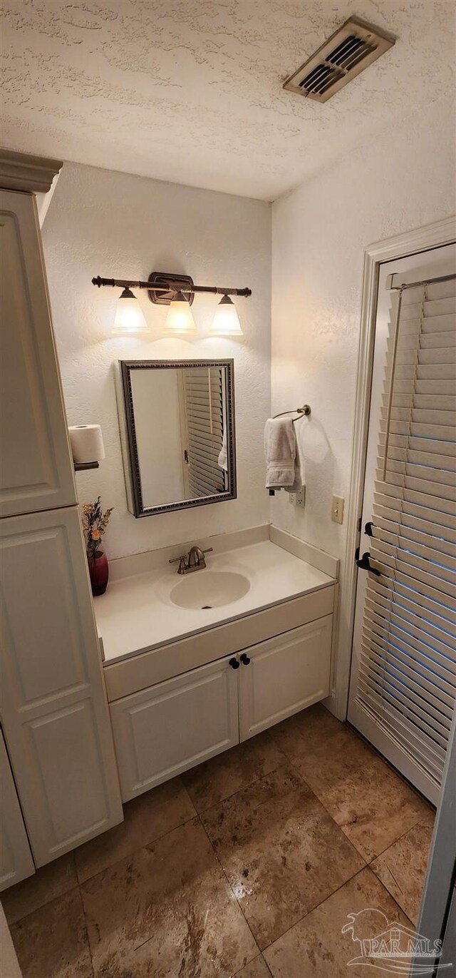 bathroom with visible vents, vanity, and a textured ceiling