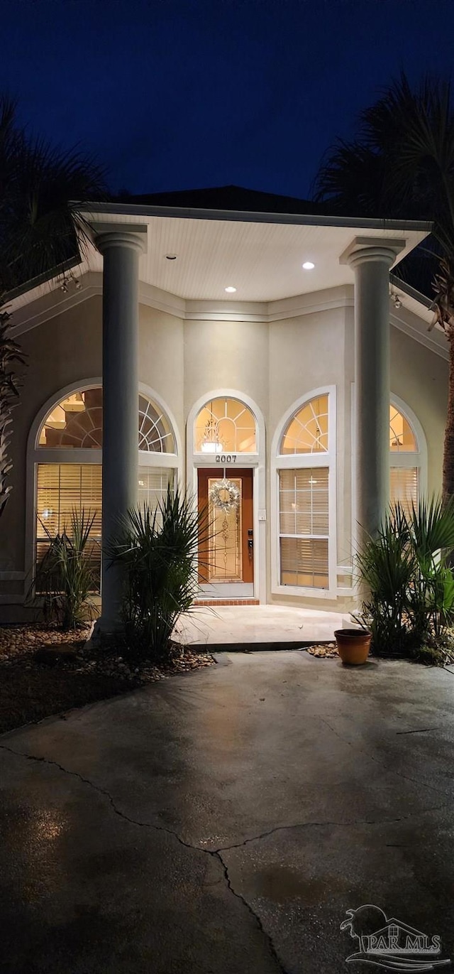 exterior entry at night featuring stucco siding