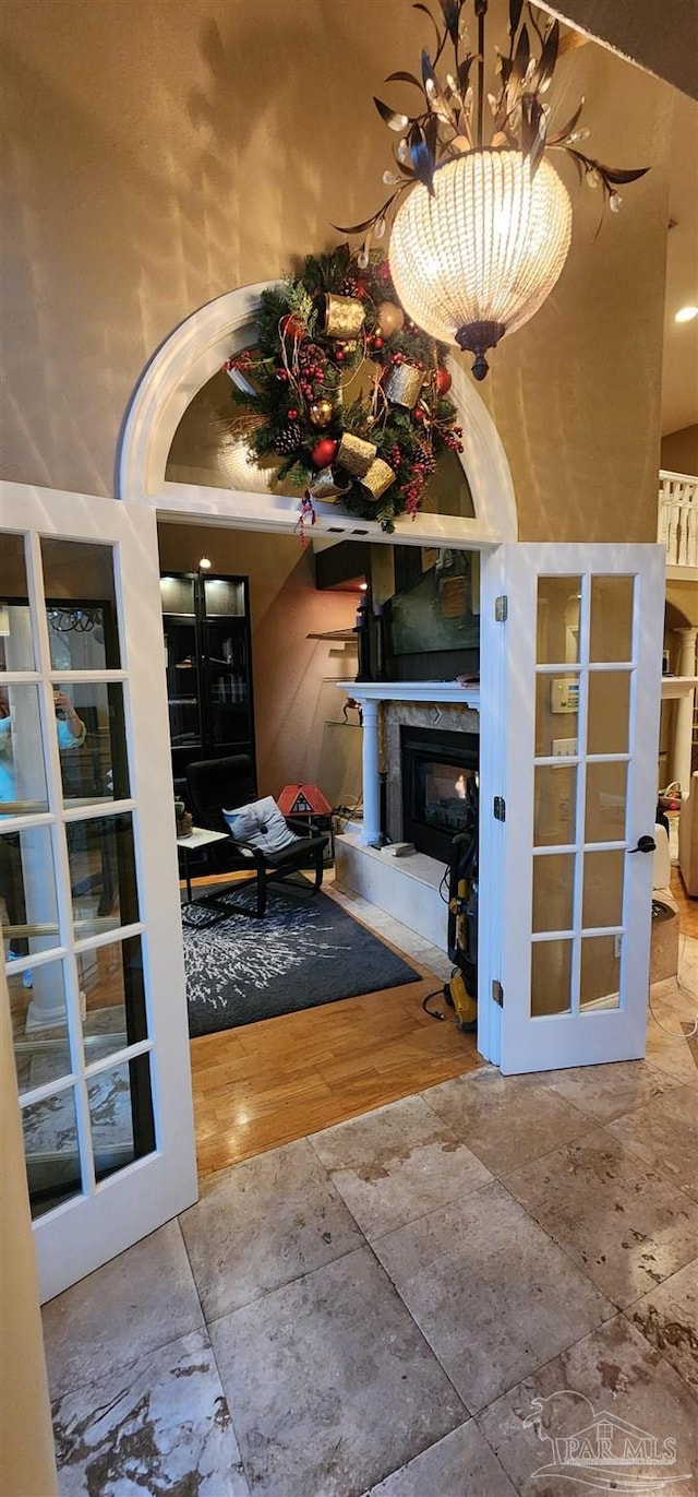 interior space with french doors, stone tile floors, and a chandelier