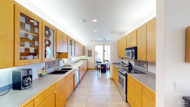 kitchen featuring tasteful backsplash, stainless steel appliances, decorative light fixtures, and light tile patterned floors