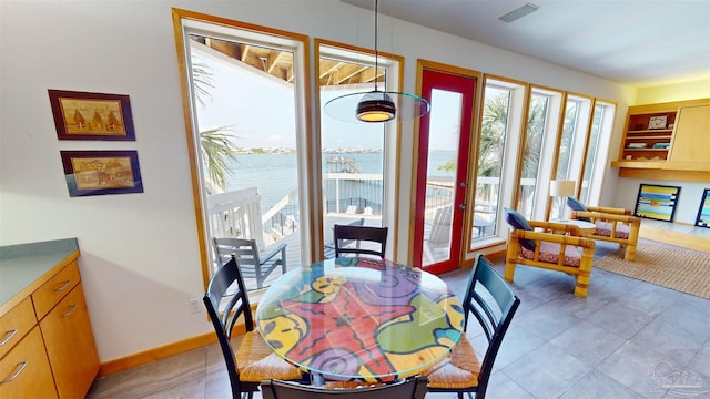 dining space featuring a water view and light tile patterned floors