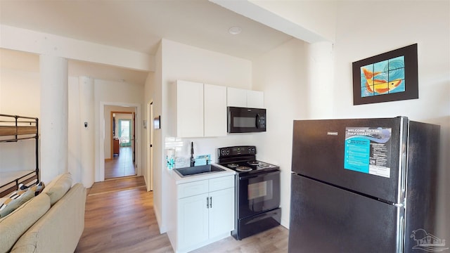 kitchen with light hardwood / wood-style flooring, black appliances, and white cabinets