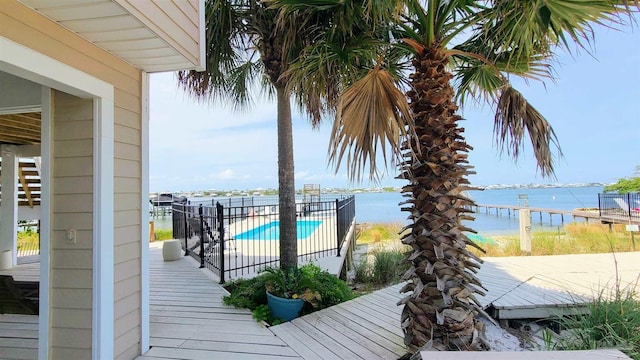 wooden deck with a water view and a fenced in pool