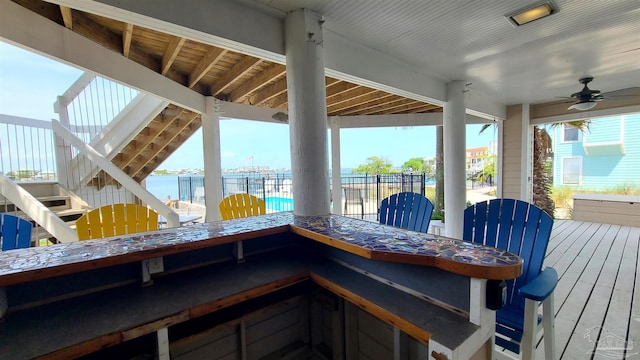 deck with a water view and ceiling fan