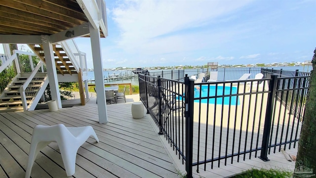 wooden terrace with a patio area, a water view, and a fenced in pool