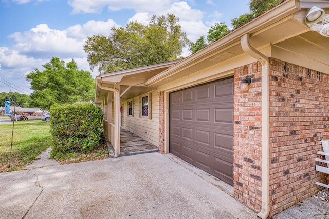 view of side of home featuring brick siding, an attached garage, and driveway