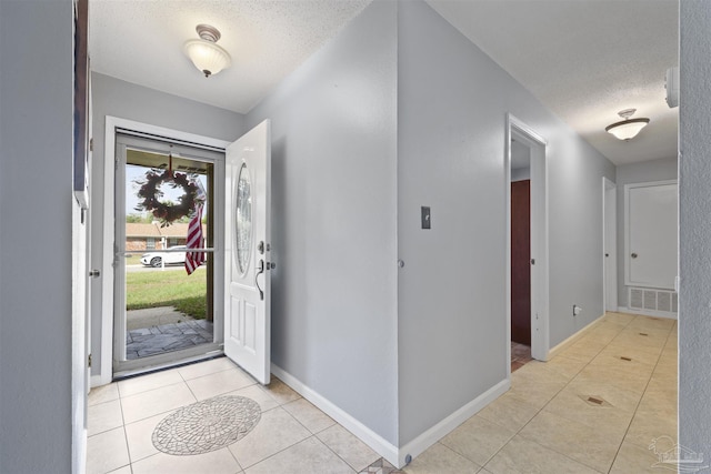 entryway with visible vents, baseboards, a textured ceiling, and light tile patterned floors
