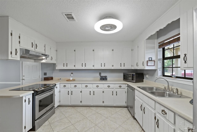 kitchen with under cabinet range hood, stainless steel appliances, light countertops, a sink, and a textured ceiling