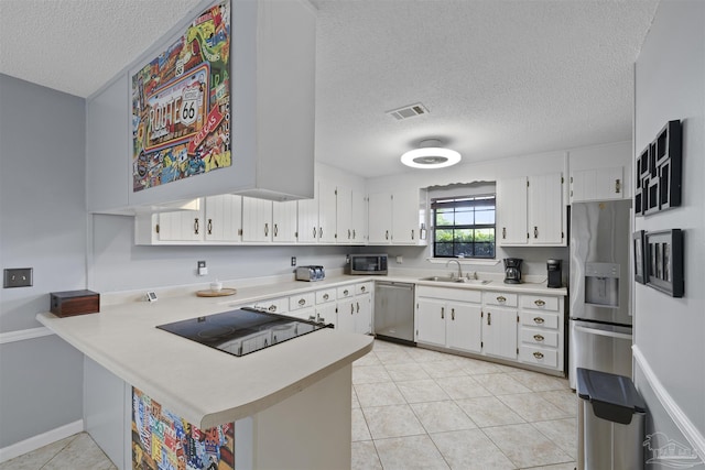 kitchen featuring a sink, a textured ceiling, light countertops, a peninsula, and appliances with stainless steel finishes