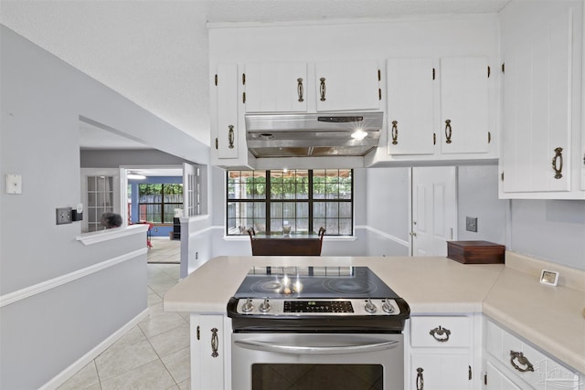 kitchen with under cabinet range hood, light countertops, light tile patterned flooring, stainless steel electric stove, and white cabinetry