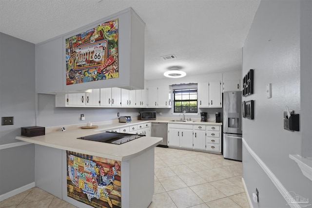 kitchen with a textured ceiling, a sink, stainless steel appliances, light countertops, and visible vents