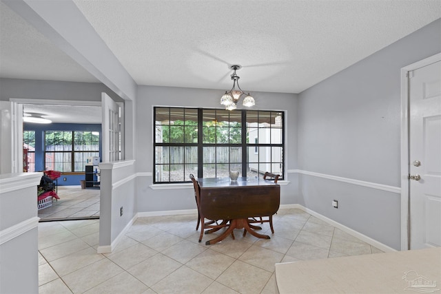 dining area featuring a chandelier, a textured ceiling, baseboards, and light tile patterned floors